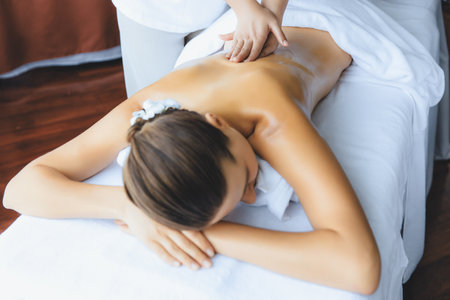 Caucasian woman customer enjoying relaxing anti-stress spa massage and pampering with beauty skin recreation leisure in day light ambient salon spa at luxury resort or hotel. Quiescentの写真素材