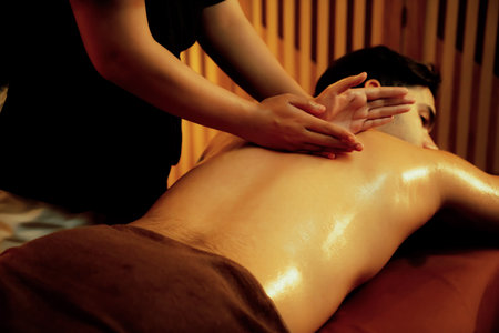 Caucasian man customer enjoying relaxing anti-stress spa massage and pampering with beauty skin recreation leisure in warm candle lighting ambient salon spa at luxury resort or hotel. Quiescentの写真素材