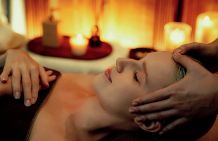 Caucasian woman enjoying relaxing anti-stress head massage and pampering facial beauty skin recreation leisure in warm candle lighting ambient salon spa in luxury resort or hotel. Quiescentの写真素材
