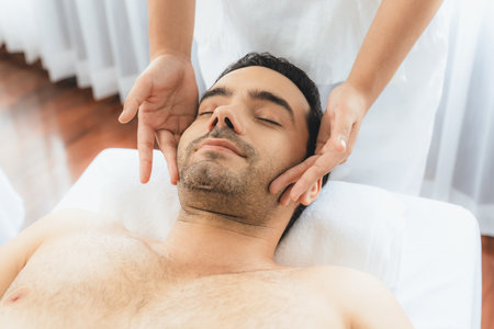 Caucasian man enjoying relaxing anti-stress head massage and pampering facial beauty skin recreation leisure in dayspa modern light ambient at luxury resort or hotel spa salon. Quiescentの写真素材