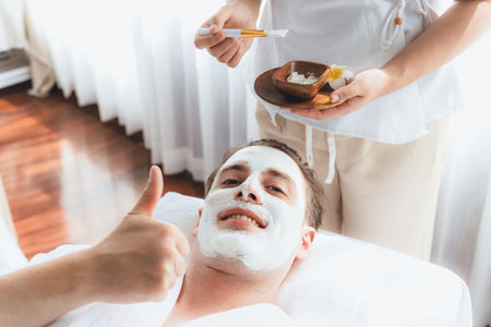 Serene ambiance of spa salon, man customer indulges in rejuvenating with luxurious face cream massage with modern daylight. Facial skin treatment and beauty care concept. Quiescentの写真素材