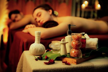 Aromatherapy massage ambiance or spa salon composition setup with focus decor candles and spa accessories on blur couple enjoying blissful aroma spa massage in resort or hotel background. Quiescentの写真素材