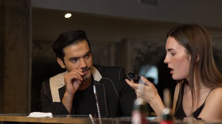 Portrait of focus beautiful woman talking with couple while looking at smartphone with serious face at bar. Capturing natural face beauty with dressing up social interaction at night club.の写真素材