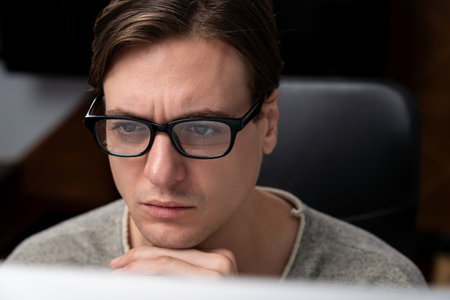 Portrait of a businessman wearing glasses in dark light, manager looking at a pc working on a creative planner project web, analyzing strategy and marketing business report at a modern office.の写真素材
