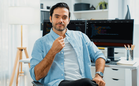Profiles smart IT developer looking camera to pose against on software development coding on two pc...