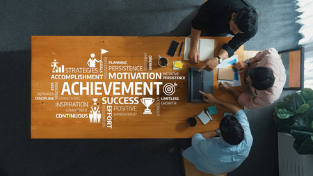 A top-down view of a collaborative business meeting focused on achievement and motivation,...