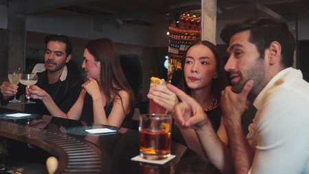 Friends or couple talking and drinking cocktail in a vibrant nightclub making a toast with friendship celebrating special party beverage.の写真素材