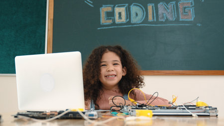 African student programming system while looking at camera. Girl working on her laptop while coding engineering program and generating AI by using software at Stem lesson.の写真素材