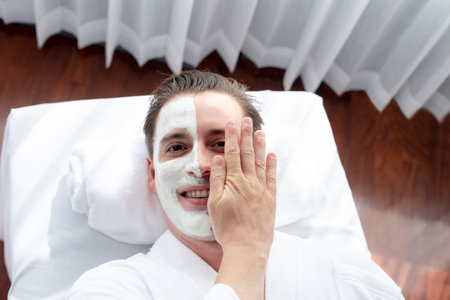 Serene ambiance of spa salon, man customer indulges in rejuvenating with luxurious face cream massage with modern daylight. Facial skin treatment and beauty care concept. Quiescentの写真素材