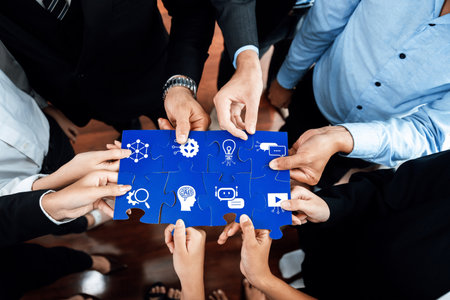A diverse group of professionals collaborates over a blue puzzle symbolizing strategic ideas and innovation, showcasing teamwork and connection in a business environment. Amityの写真素材