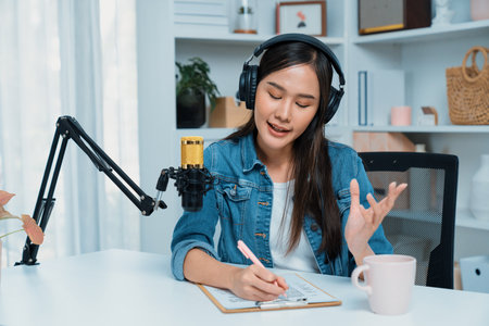 Host channel of young beautiful Asian wearing jeans creative broadcaster talking in online broadcast explaining to promote marketing or consultant in daily life with listener at studio. Stratagem.の写真素材