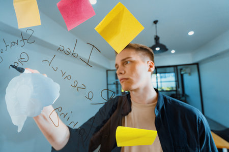 Professional caucasian businessman writing marketing idea by using mind map and sticky notes on glass board at modern meeting room. Creative business and planing concept. Closeup. Immaculate.の写真素材