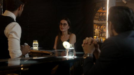 Focusing on beautiful woman guest sitting in special drink gin fizz at luxurious counter bar at...