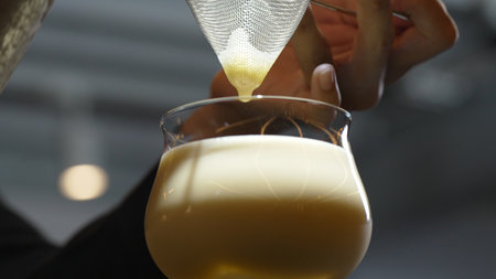 Closeup hand bartender using strainer in all ingredients alcohol liquor and syrup tasty in cocktail glass serving special refresh drink showcasing nightlife mixology at luxurious nightclub. Vinosity.の写真素材