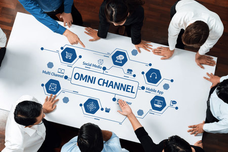 A group of business professionals engages in a collaborative meeting, analyzing an omni-channel strategy on a large table, showcasing diverse marketing concepts and insights for growth.の写真素材