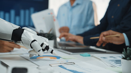 A robotic arm collaborates with human hands in a modern office, analyzing business data and documents, showcasing the integration of technology in the workspace.の写真素材