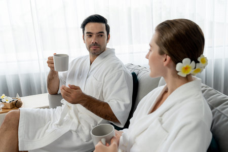 Beauty or body treatment spa salon vacation lifestyle concept with couple wearing bathrobe relaxing with drinks in luxurious hotel spa or resort room. Vacation and leisure relaxation. Quiescentの写真素材