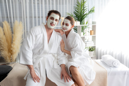 Blissful couple in bathrobe with facial cream mask enjoying serene ambiance of spa salon resort or hotel during holiday. Pampering face spa and skincare treatment with essence relaxation. Quiescentの写真素材