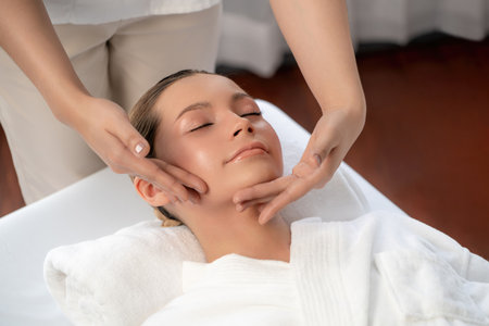 Caucasian woman enjoying relaxing anti-stress head massage and pampering facial beauty skin recreation leisure in dayspa modern light ambient at luxury resort or hotel spa salon. Quiescentの写真素材