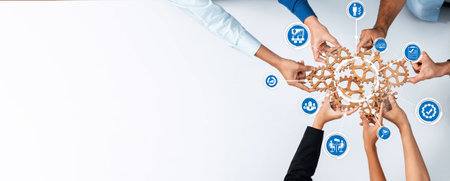This image depicts diverse hands collaborating over a unified business concept represented by icons, symbolizing teamwork, strategy, and innovation in management. Amityの写真素材