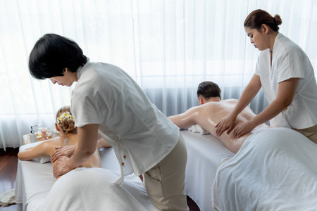 Caucasian couple customer enjoying relaxing anti-stress spa massage and pampering with beauty skin recreation leisure in day light ambient salon spa at luxury resort or hotel. Quiescentの写真素材