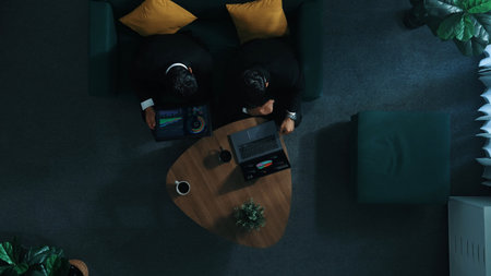 Top down aerial view of businessman sitting while working on laptop while skilled colleague walking in to room and analyze financial data together. Business team sharing marketing idea. Directorate.の写真素材