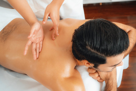 Caucasian man customer enjoying relaxing anti-stress spa massage and pampering with beauty skin recreation leisure in day light ambient salon spa at luxury resort or hotel. Quiescentの写真素材