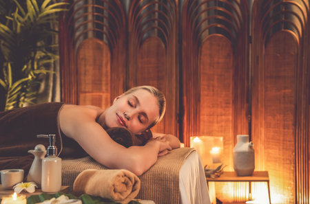 Caucasian woman customer enjoying relaxing anti-stress spa massage and pampering with beauty skin recreation leisure in warm candle lighting ambient salon spa at luxury resort or hotel. Quiescentの写真素材