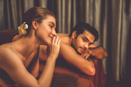 Caucasian couple customer enjoying relaxing anti-stress spa massage and pampering with beauty skin recreation leisure in warm candle lighting ambient salon spa at luxury resort or hotel. Quiescentの写真素材
