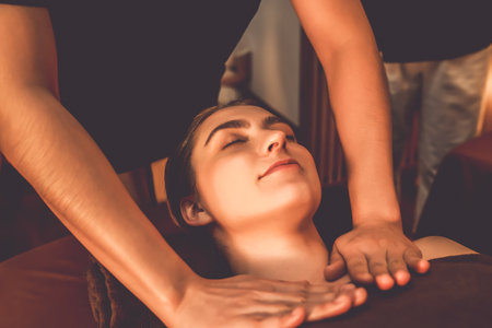 Caucasian woman customer enjoying relaxing anti-stress spa massage and pampering with beauty skin recreation leisure in warm candle lighting ambient salon spa at luxury resort or hotel. Quiescentの写真素材