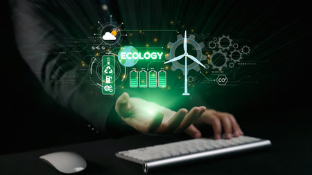 A hand positioned near a computer keyboard displays an innovative ecology concept, showcasing sustainable energy symbols like wind turbines and battery icons against a dark background. Qubitの写真素材