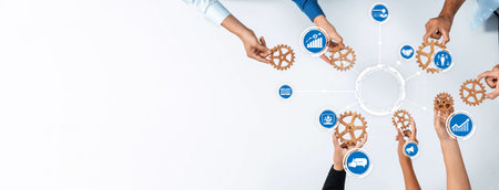 A top-down view of diverse hands holding gears and icons representing business themes. This image symbolizes teamwork, collaboration, and strategic planning in a modern workspace. Amityの写真素材