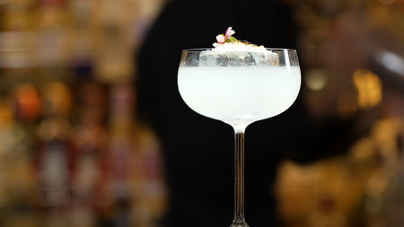 Closeup of bartender using strainer in vodka coconut smooth fizzy cocktail at luxurious counter preparation making special to guest at fronted bar. Special refresh showcasing nightlife.の写真素材