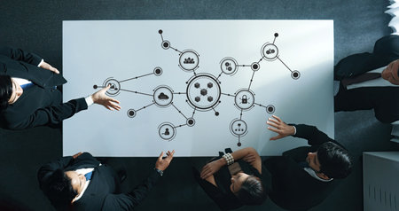 Aerial view of business professionals collaborating at a modern conference table. The image illustrates a digital network concept symbolizing connections and data flow. Amityの写真素材