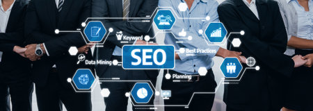 A group of business professionals in suits stands together, discussing SEO strategies, data mining techniques, and best practices in a modern office environment. Amityの写真素材