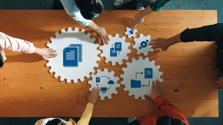 Discover a vibrant management strategy session where diverse hands collaboratively position icons on gear shapes. Visualize teamwork and innovation in a business environment.の写真素材