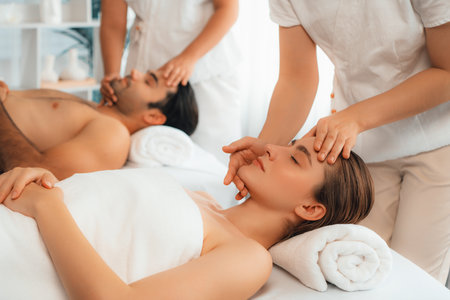 Caucasian couple enjoying relaxing anti-stress head massage and pampering facial beauty skin recreation leisure in dayspa modern light ambient at luxury resort or hotel spa salon. Quiescentの写真素材