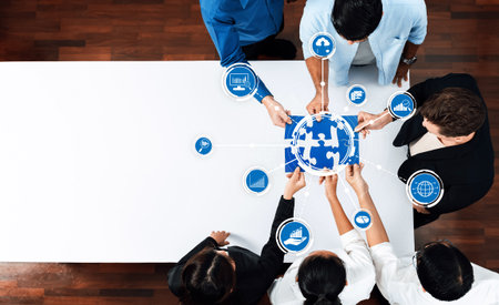 A group of diverse professionals engages collaboratively in a strategy session, working together on a global puzzle to devise innovative solutions and data-driven insights.の写真素材