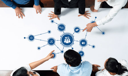 A group of professionals collaborates around a table, focusing on digital media connections and networking strategy, highlighting teamwork and interaction. Amityの写真素材