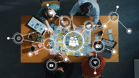 A vibrant overhead view of a collaborative brainstorming session showcasing diverse individuals engaging in idea generation with digital media icons symbolizing communication and technology.の写真素材