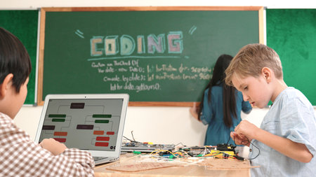 Asian boy coding program while caucasian friend fixing electric board at STEM class. Energetic student standing blackboard while writing coding engineering prompt and programming AI software.の写真素材