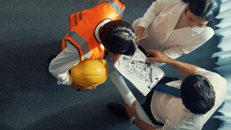 Top view of skilled architect engineer team looking at blueprint together. Aerial view of smart designer holding tablet while working together and brainstorming about building structure.の写真素材