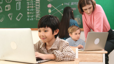 Cute boy coding engineering while attractive girl drawing picture at blackboard. Caucasian boy...