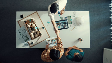 Top view of architect engineer working together and shaking hand cooperative team while making...