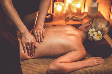 Caucasian woman customer enjoying relaxing anti-stress spa massage and pampering with beauty skin recreation leisure in warm candle lighting ambient salon spa at luxury resort or hotel. Quiescentの写真素材