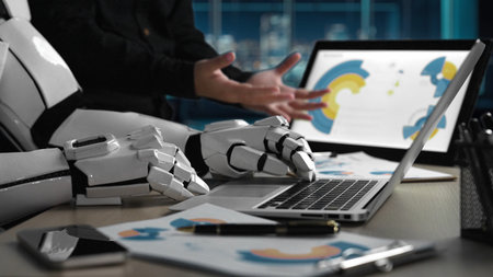 A sleek robotic arm interacts with a laptop and documents in a modern workspace, showcasing the blend of technology and innovation in today's digital environment.の写真素材