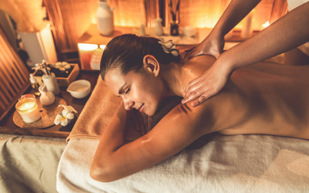 Caucasian woman customer enjoying relaxing anti-stress spa massage and pampering with beauty skin recreation leisure in warm candle lighting ambient salon spa at luxury resort or hotel. Quiescentの写真素材