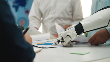 A futuristic robot arm points to business data and charts during a collaborative meeting, showcasing the integration of technology in modern corporate strategy discussions.Noogenesisの写真素材
