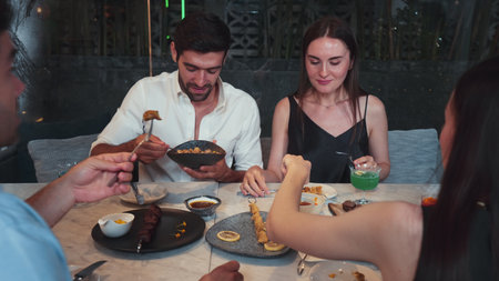Group friend or couple discussing with smartphone while having dinner at grill and crispy meat main course table. Theme of meeting in friendship impressive occasion at luxurious restaurant. Vinosity.の写真素材