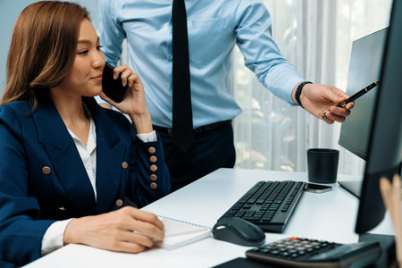 Businesswoman calling with business partner on mobile phone while calculating stock exchange value data with man in casual pointing on pc, analyzing company value sell or buy on up to date. Infobahn.の写真素材